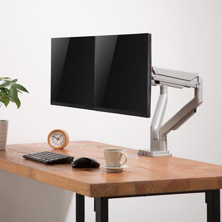 Echo Dual Monitor Arm, silver, mounted on a butcher block desktop, front angle view.