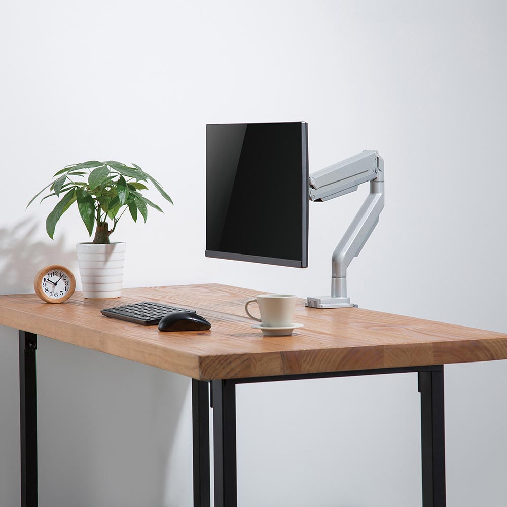 Echo Single Monitor Arm, shown in silver, on a butcher block desktop.